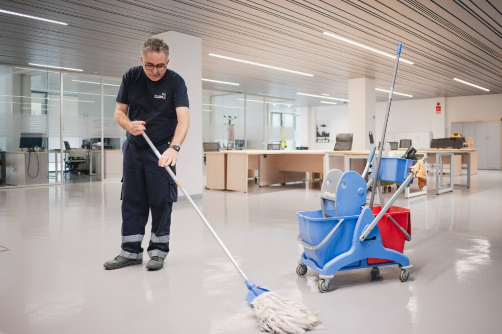 Empresa de limpieza de oficinas. Trabajador limpiando el suelo de una zona común de una oficina
